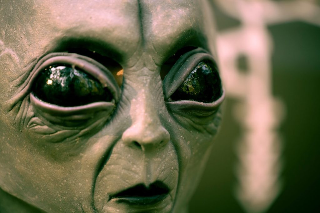 Detailed close-up of an alien face mask with black eyes, perfect for Halloween or sci-fi themes.