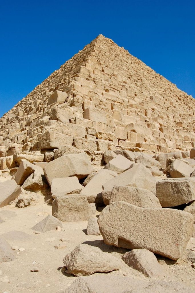 A low-angle shot of an ancient Egyptian pyramid against a clear blue sky.