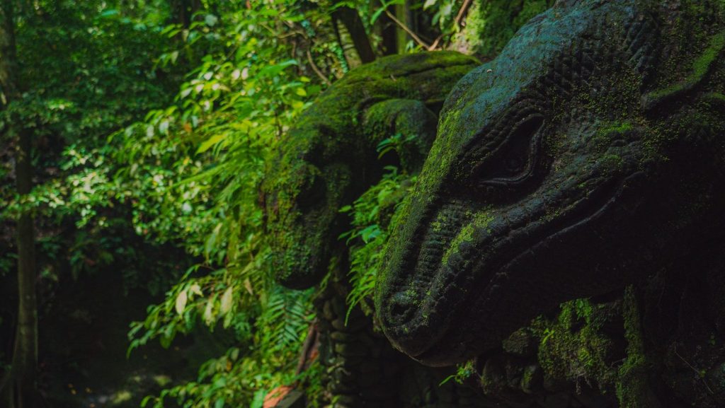 Two dinosaur heads covered in moss are seen.