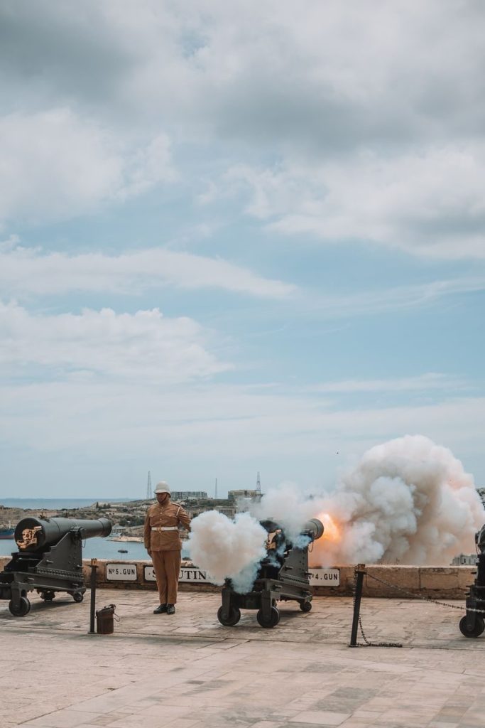 A traditional cannon firing ceremony in Valletta, Malta, showcasing historical attire and artillery.