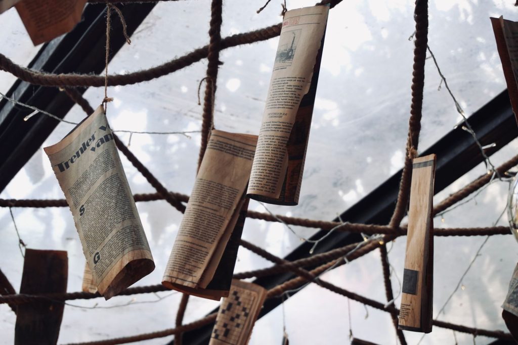 Ceiling display of hanging vintage newspapers on ropes indoors, artistic decor.