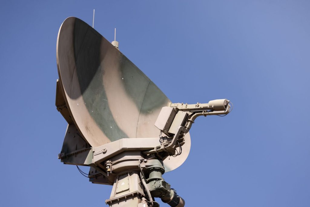 Close-up of a military radar system with a clear blue sky as background, showcasing advanced communication technology.