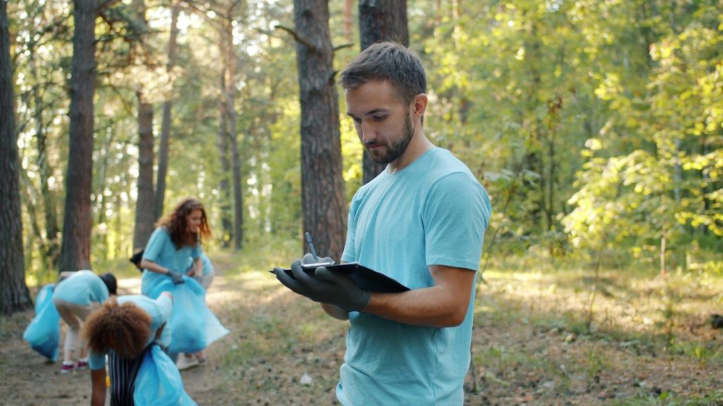 Volunteers cleaning up a forest with trash bags.