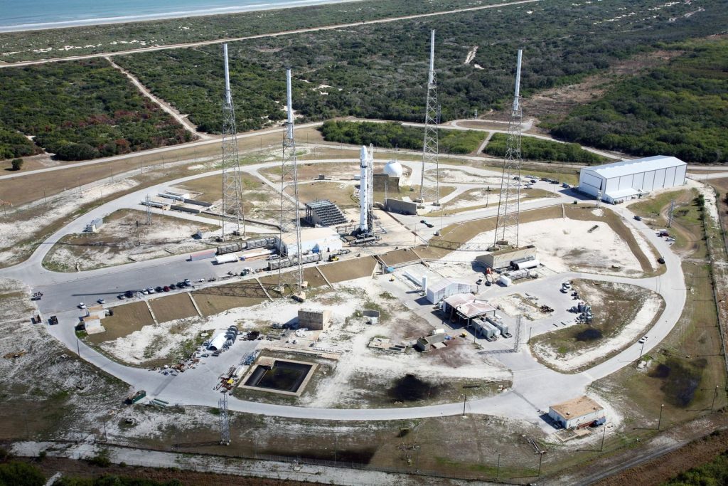 Drone view of spaceport with installed rocket ready for launching steel towers and hangar located amidst green forest
