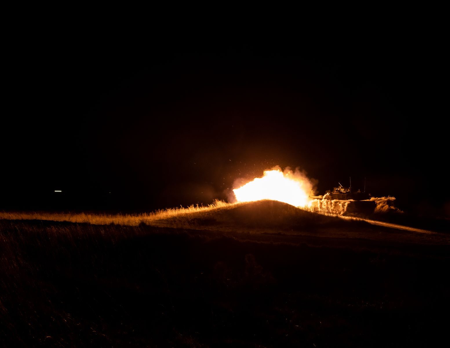 A powerful fireball eruption during nighttime military training creates a dramatic scene.