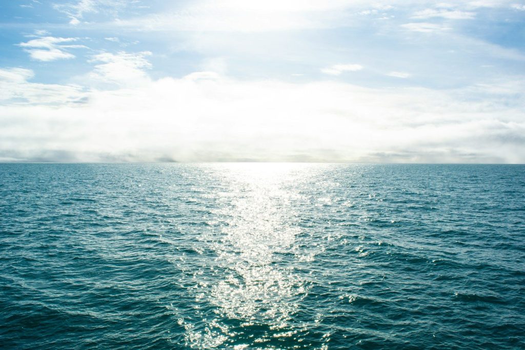 a body of water with the sun shining through the clouds