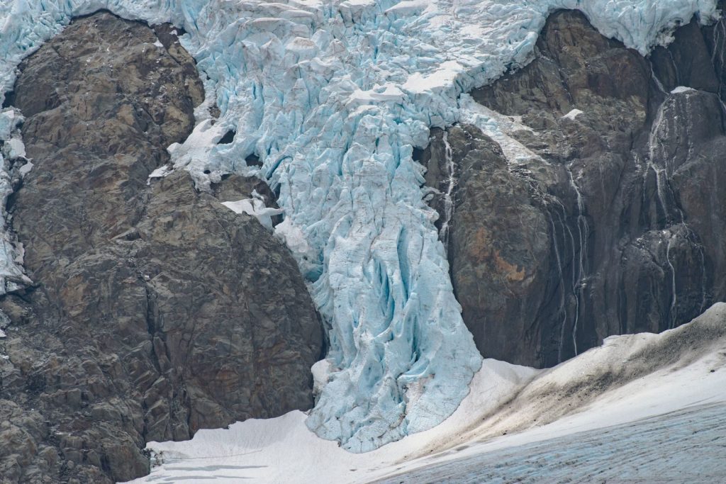 Close-up of a stunning glacier cascading down a rocky mountain in winter, showcasing intricate ice formations.