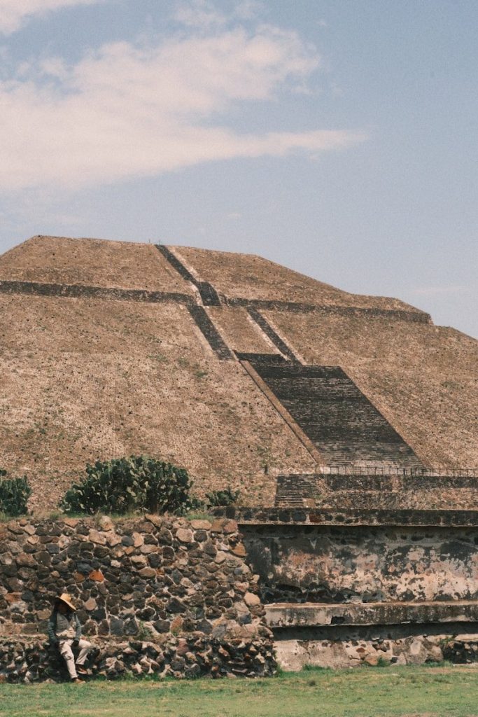 Ancient stepped pyramid with a person in the foreground.
