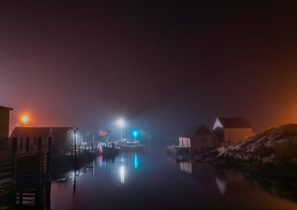 a body of water with buildings along it and a bridge with lights