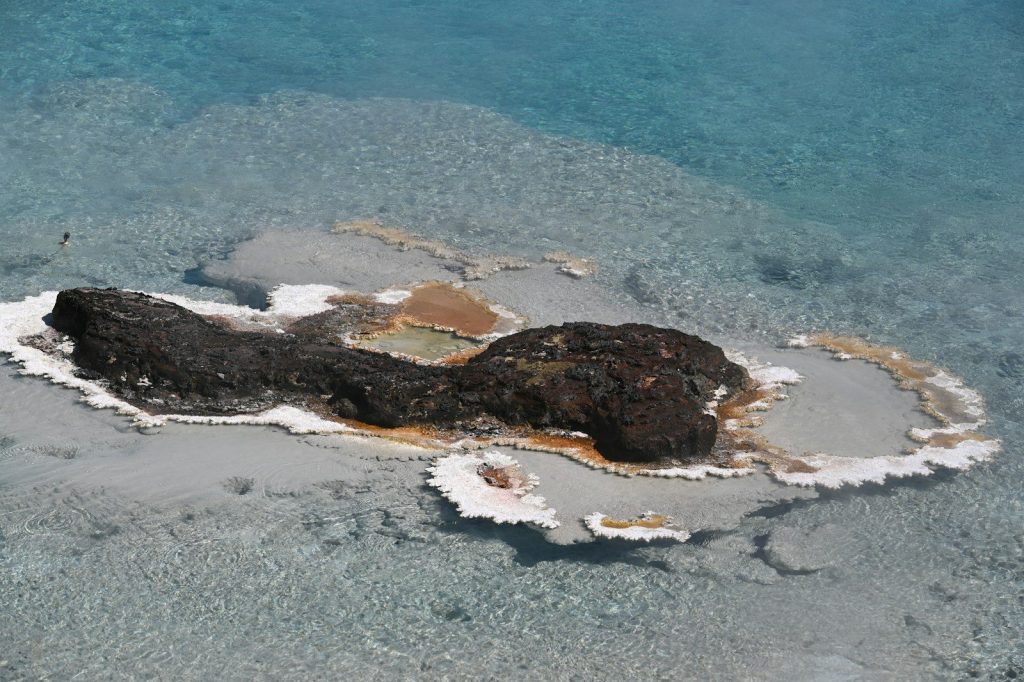 brown and white rock formation on body of water during daytime