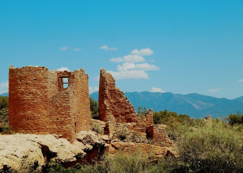 Ancient stone ruins on a rocky cliff under blue sky.