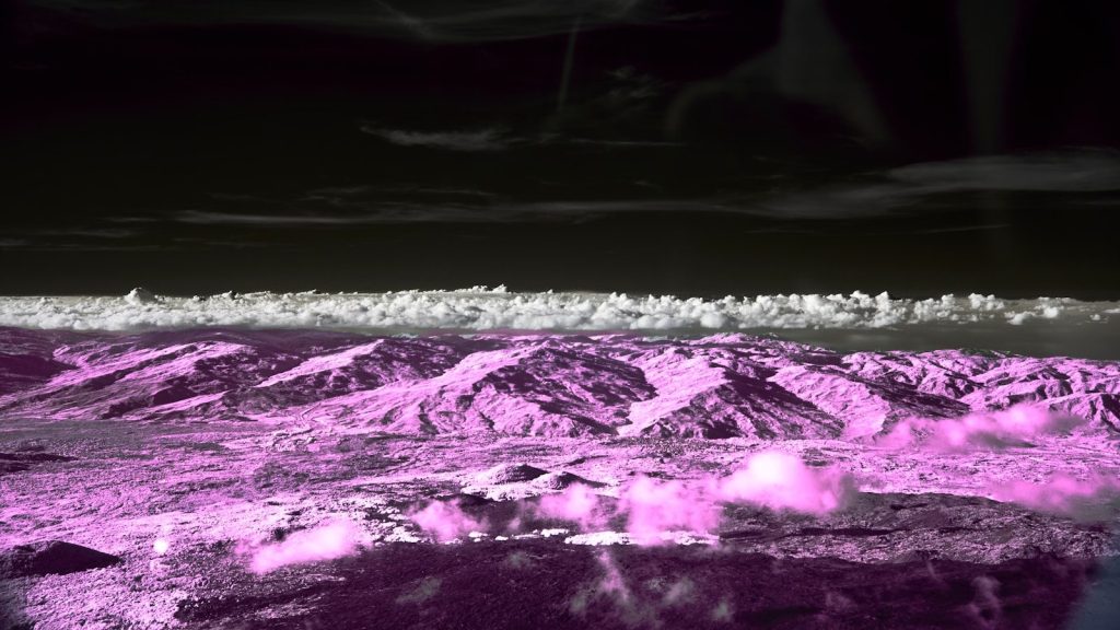 Pink mountains under a dark, cloudy sky