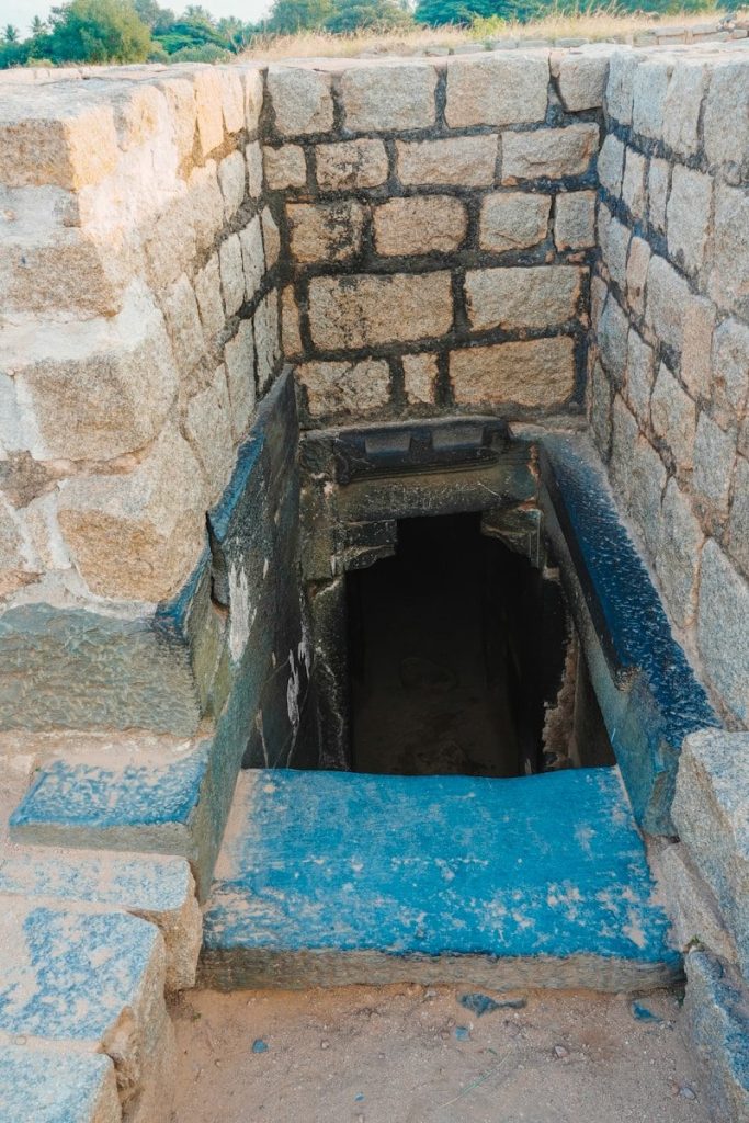 Stone steps lead down into a dark opening.