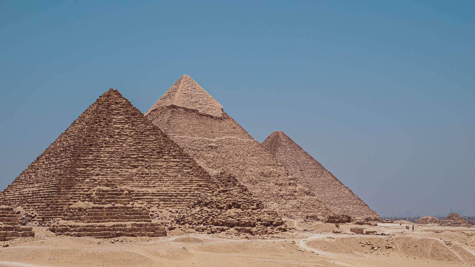 three pyramids in the desert with a blue sky in the background