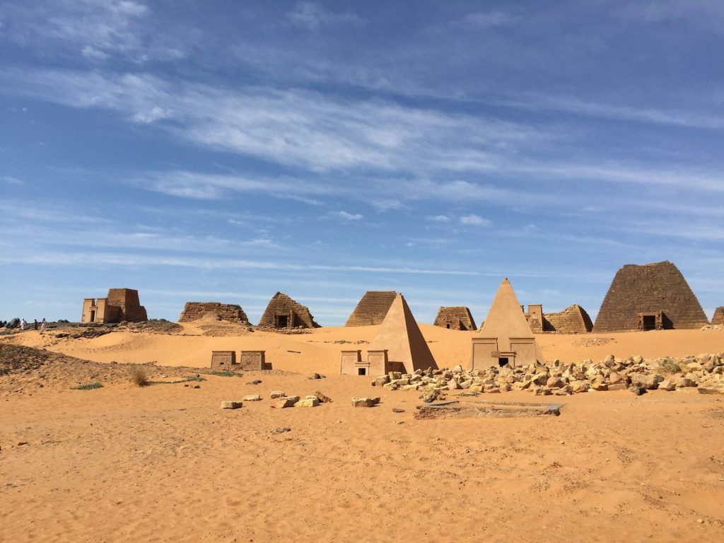 Ancient pyramids stand in a vast desert landscape.