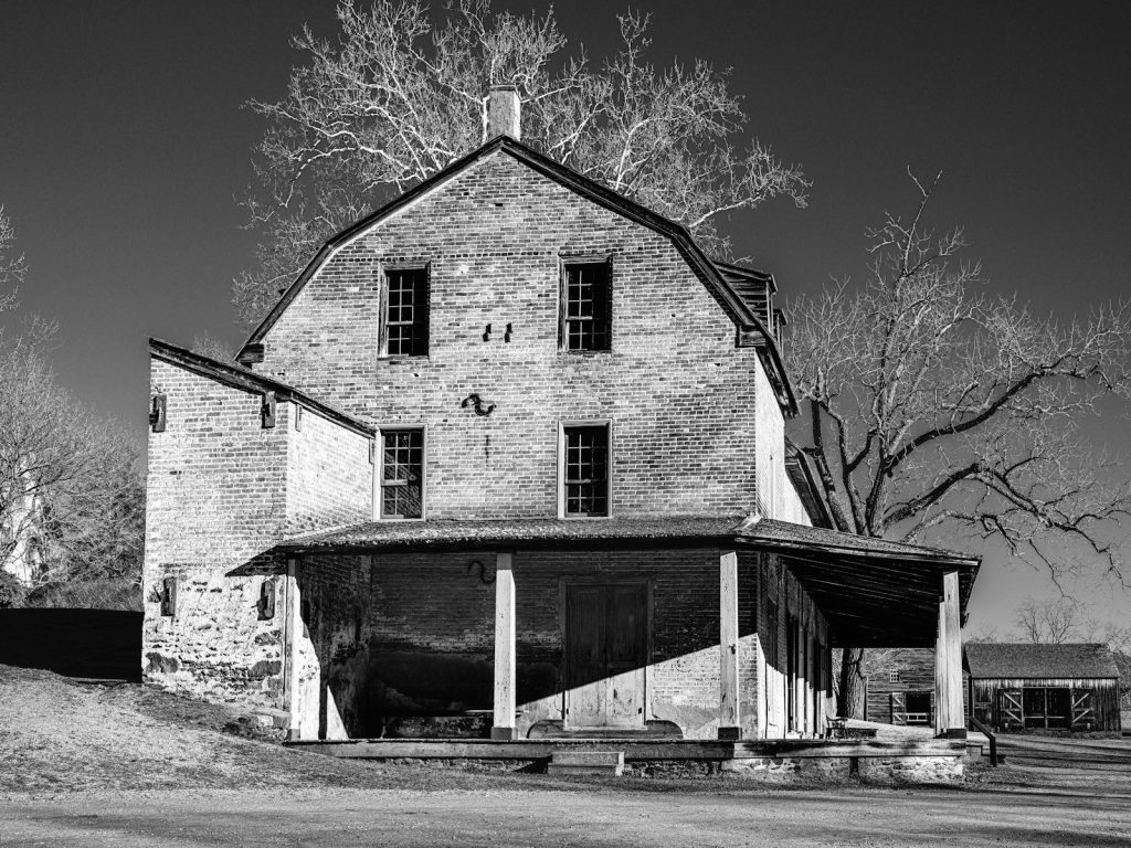 Old brick building with a covered porch and trees
