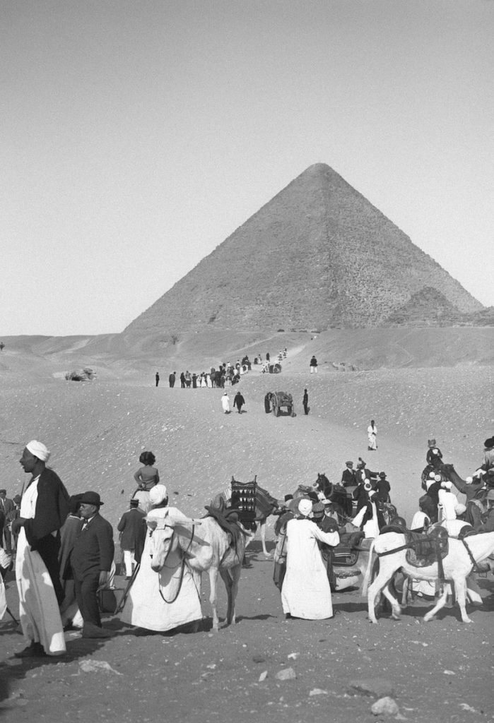 People and camels near a pyramid in the desert