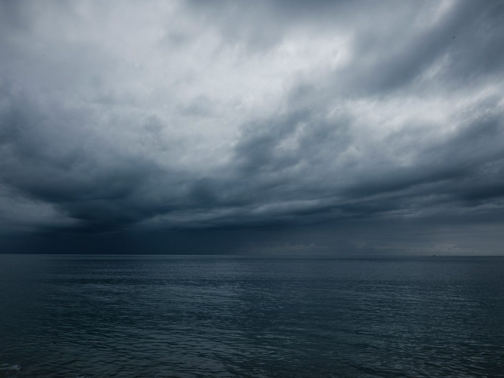 Dark atmospheric sky over quiet ocean at dawn